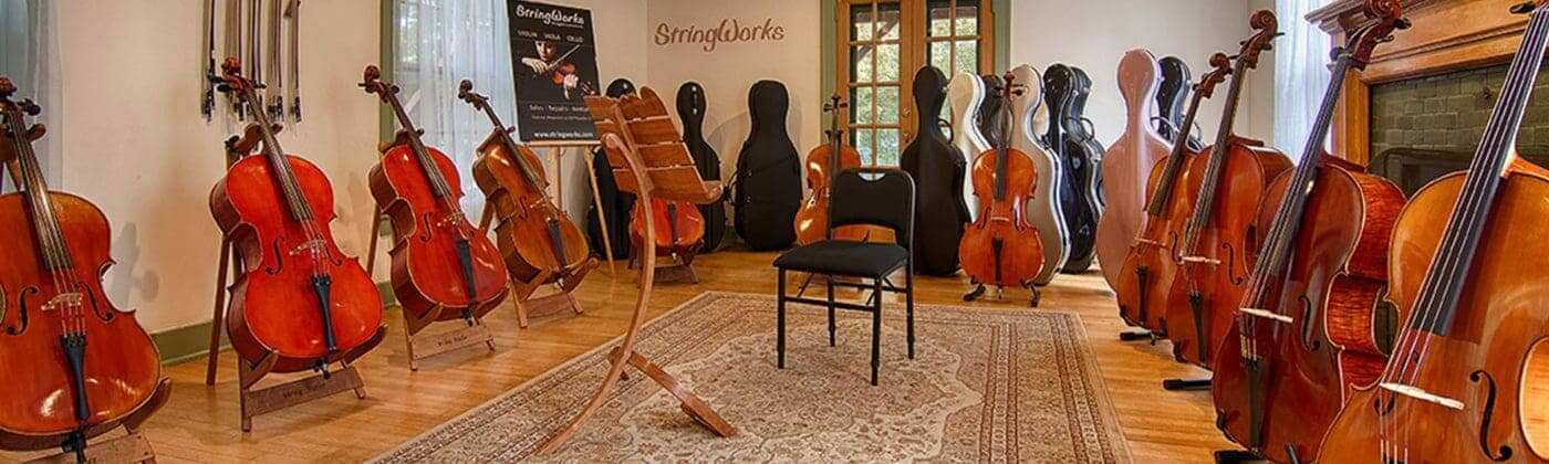 StringWorks violin workshop interior showing professional luthier workbench with handcrafted violins, violas, and cellos during setup process